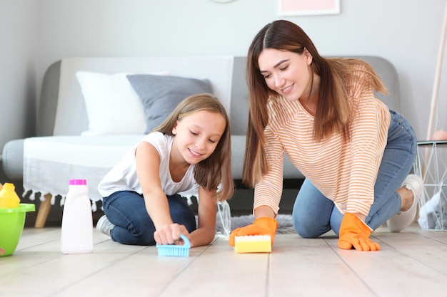 Mother and daughter in a good mood are cleaning the house