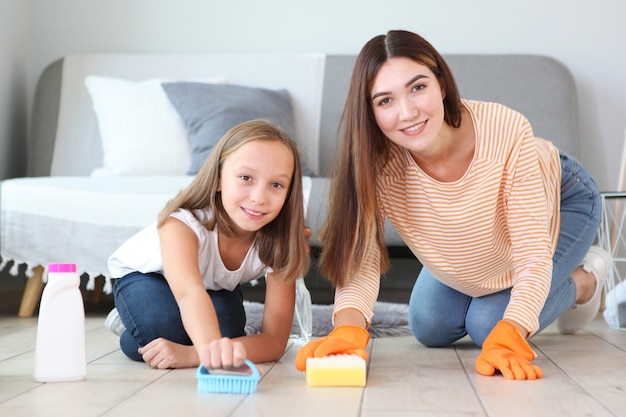 Mother and daughter in a good mood are cleaning the house