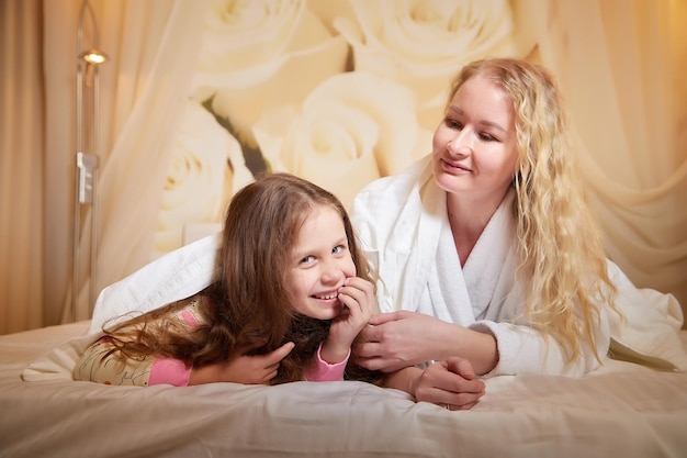 Photo mother and daughter happily relax and fun together on a bed in bedroom the concept of tenderness