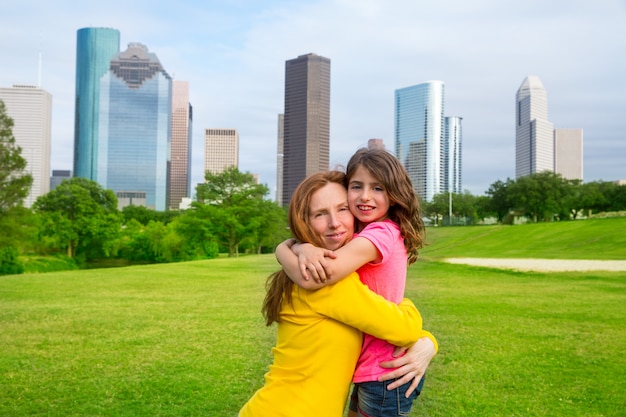 Mother and daughter happy hug in park at city skyline