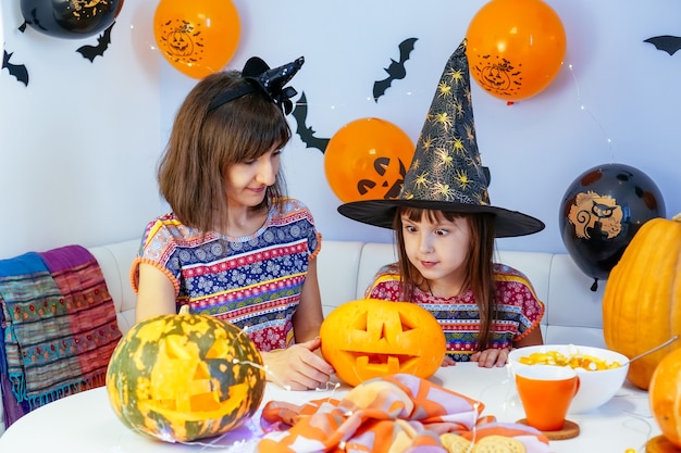 Mother and daughter have fun cleaning out insides of pumpkin to make jack o lantern for halloween