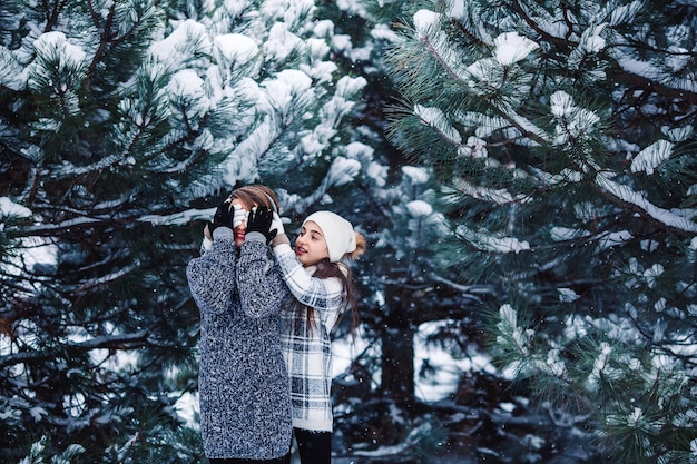 Mother and daughter have fun playing in the winter forest.