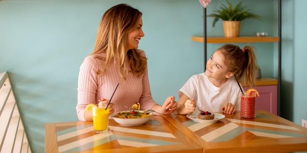 Mother and daughter having a breakfast with fresh squeezed juices in the cafe