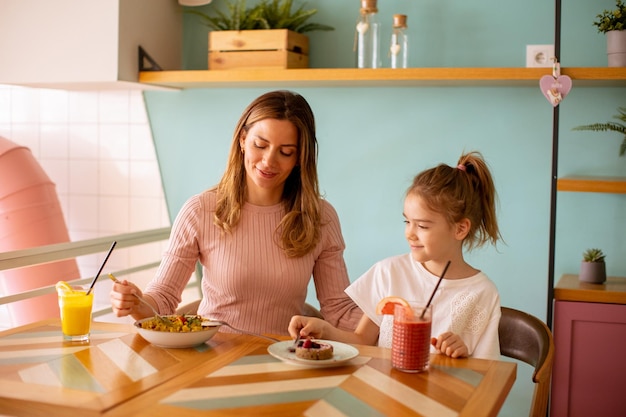 Mother and daughter having a breakfast with fresh squeezed juices in the cafe