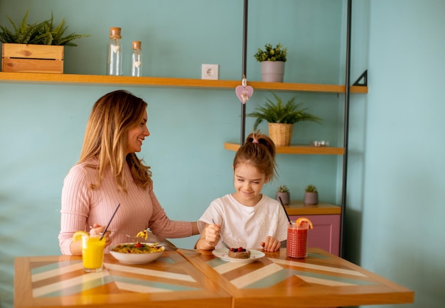 Mother and daughter having a breakfast with fresh squeezed juices in the cafe