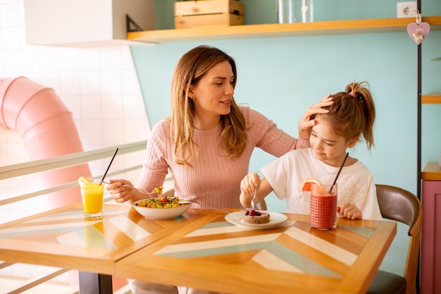 Mother and daughter having a breakfast with fresh squeezed juices in the cafe