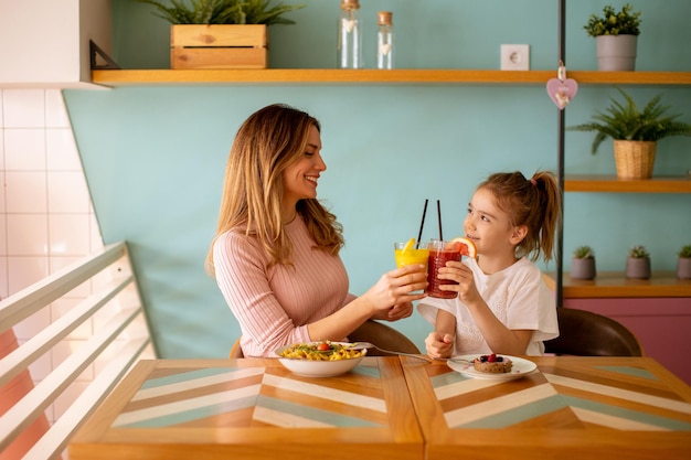 Mother and daughter having a breakfast with fresh squeezed juices in the cafe