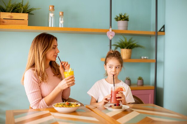 Mother and daughter having a breakfast with fresh squeezed juices in the cafe