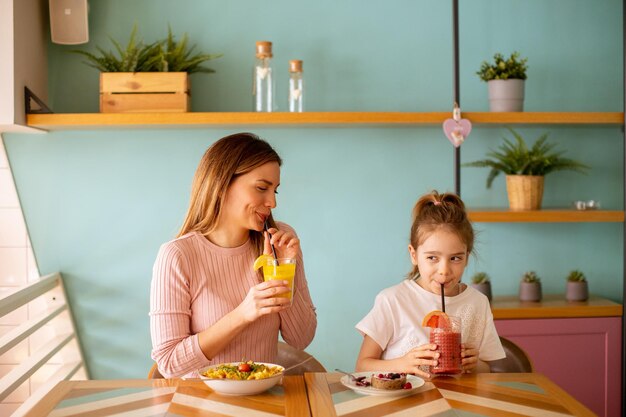 Mother and daughter having a breakfast with fresh squeezed juices in the cafe