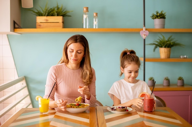 Mother and daughter having a breakfast with fresh squeezed juices in the cafe