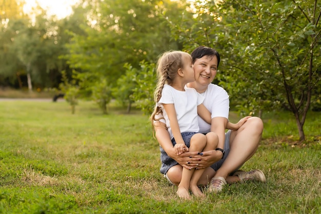 Mother and daughter having fun in the park. Happy family concept. Beauty nature scene with family outdoor lifestyle. Happy family resting together. Happiness and harmony in family life.