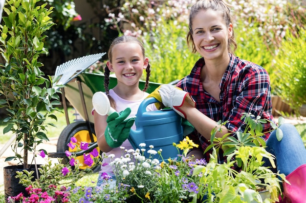 Foto madre e figlia che tengono un annaffiatoio mentre facendo il giardinaggio