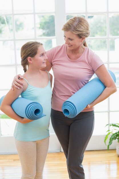 Mother and daughter holding yoga mats 