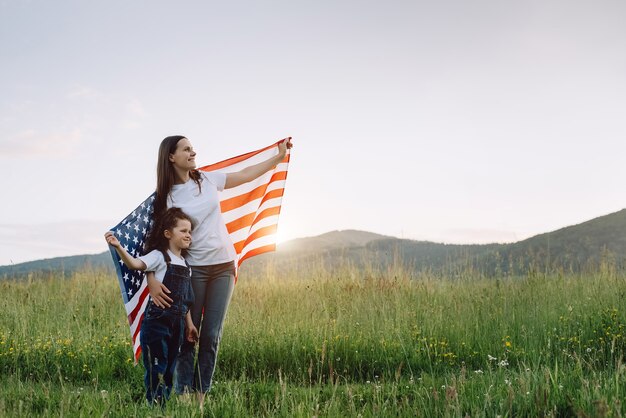 mother and daughter holds usa united states flag