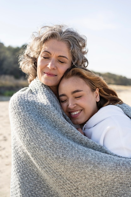 Foto madre e figlia che si abbracciano all'aperto in spiaggia