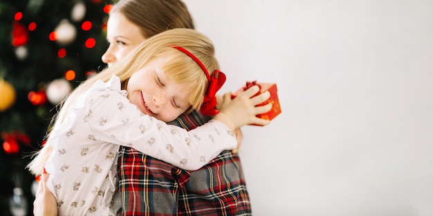 Mother and daughter hugging in front of christmas tree