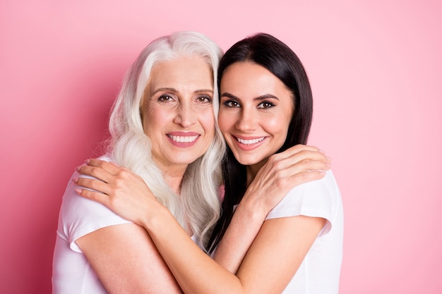 mother and daughter hugging isolated on pink