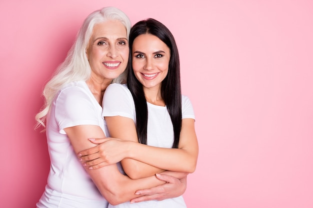 mother and daughter hugging isolated on pink