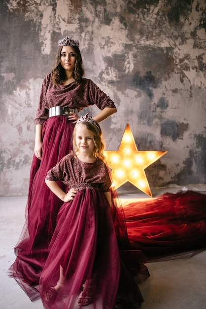 Mother and daughter in the image of the queen and princess dresses in the colors of Marsala with a long train in the loft