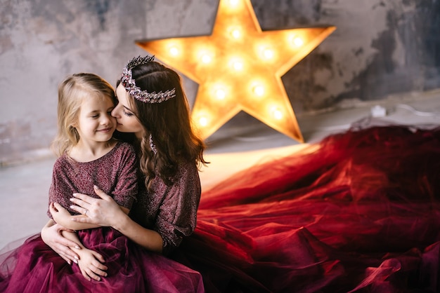 Mother and daughter in the image of the queen and princess dresses in the colors of Marsala with a long train in the loft
