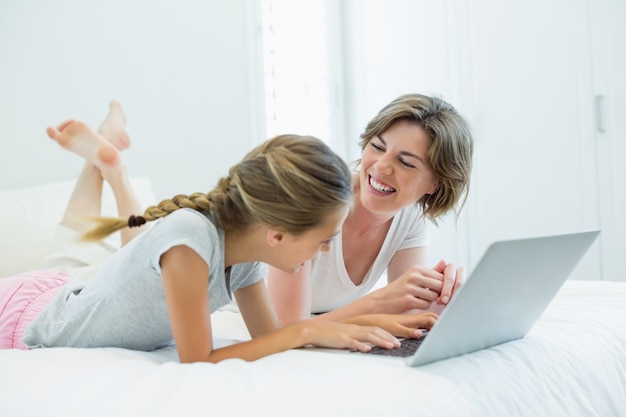엄마와 딸이 침대에서 노트북을 사용하는 동안 서로 상호 작용