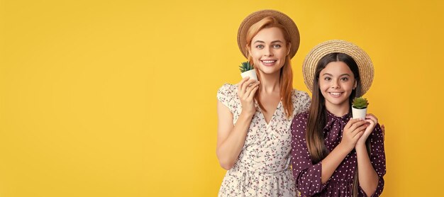 Mother and daughter kid banner copy space isolated background smiling mother and daughter with plant in pot on yellow background