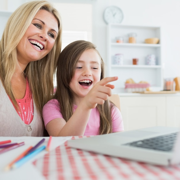 Mother and daughter laughing at laptop