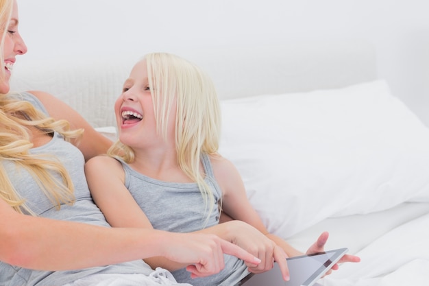 Mother and daughter laughing while using a tablet