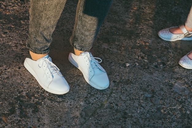 Mother and daughter legs and shoes on the asphalt, only feet