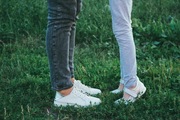 Madre e figlia gambe e scarpe sull'erba, solo piedi