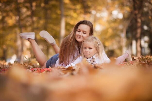 Mother and daughter lie in the park on autumn foliage