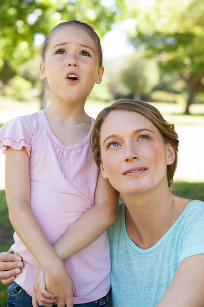 Mother and daughter looking up at park