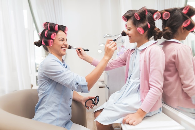 Mother and daughter make makeup to each other.