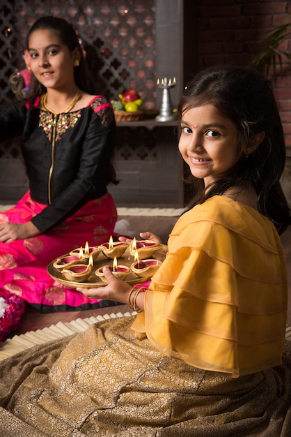 Foto madre e figlia che fanno fiori rangoli e ragazza che illuminano diya o samai