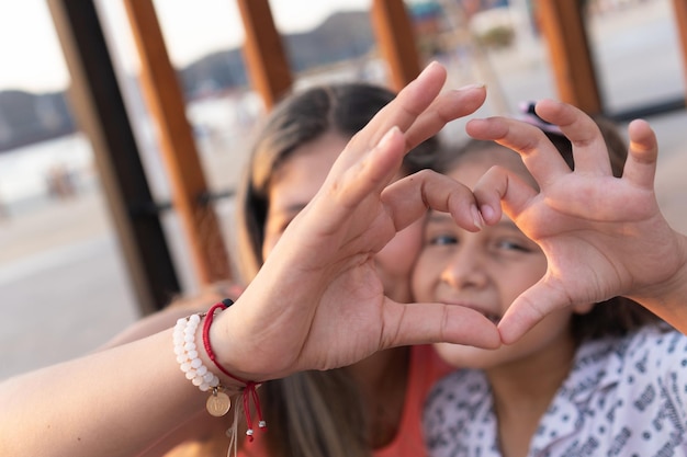 Mother and daughter making a heart by hand in the park