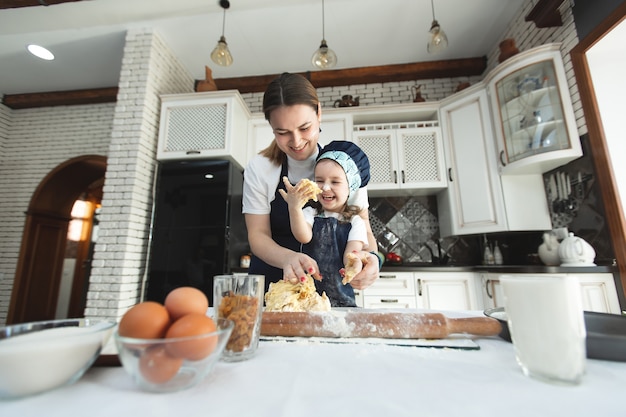 Mother and daughter in matching aprons and chef's hat cooking in the kitchen