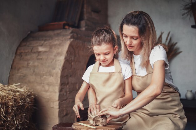 Mother and daughter mold with clay, enjoying pottery art and production process