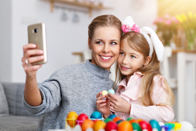 mother and daughter painting Easter eggs and taking selfie