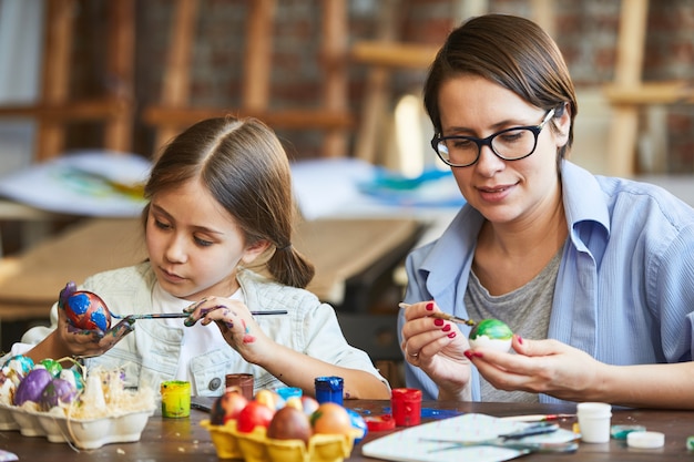 Madre e figlia che dipingono le uova di pasqua