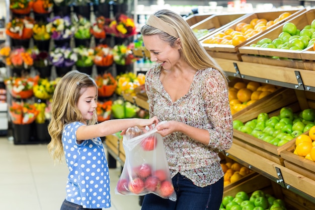 Mother and daughter picking out apple in supermarket