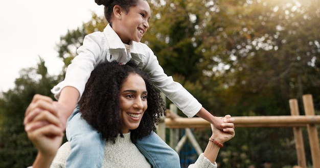 Mother daughter and piggyback walking in park or garden for fun bonding holiday or weekend outside Happy mom carrying her child on shoulders for family time together in nature or forest by house