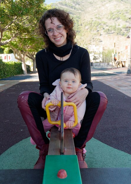 Mother and daughter playing on the park seesaw.