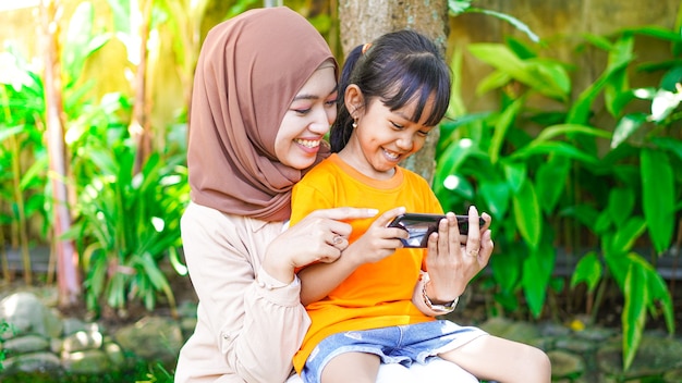 Mother and daughter playing the phone in the park