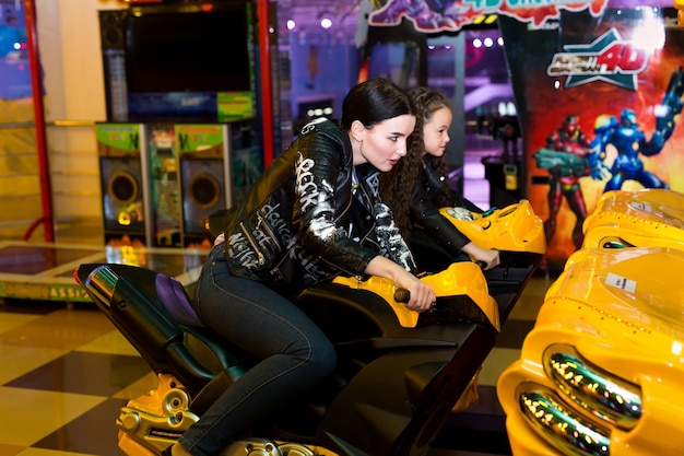 Photo mother and daughter playing slot machines, motorcycle racing