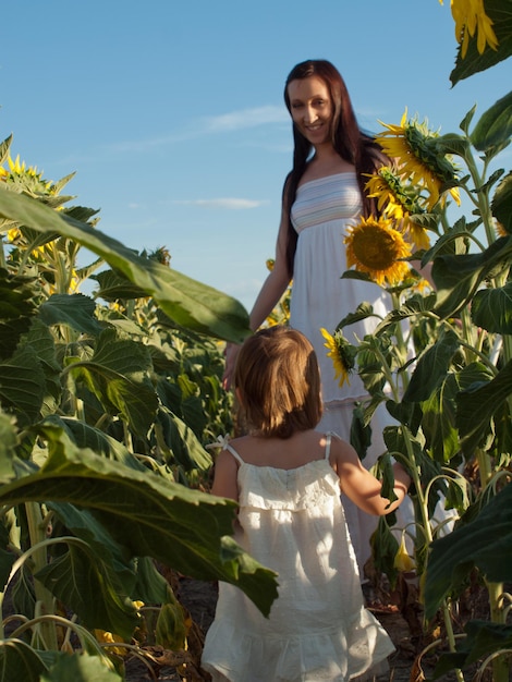 Mother and daughter playing in sunflower field.