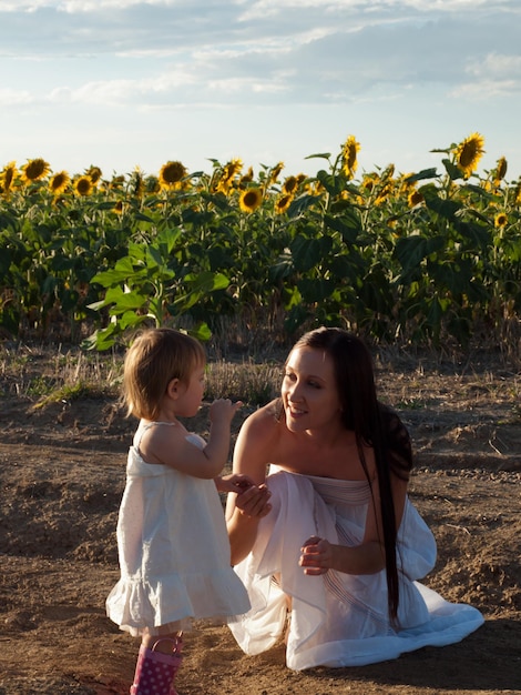 Mother and daughter playing in sunflower field.