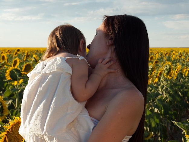 Mother and daughter playing in sunflower field.