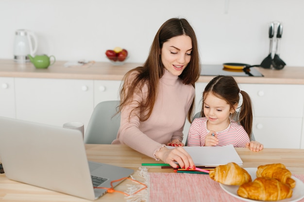 Mother and daughter playing while having breakfast in the kitchen.