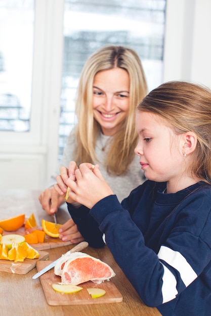 Mother and daughter playing with fruits at home