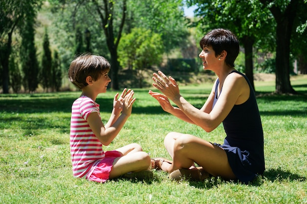 母と娘の都市公園で手で遊んで